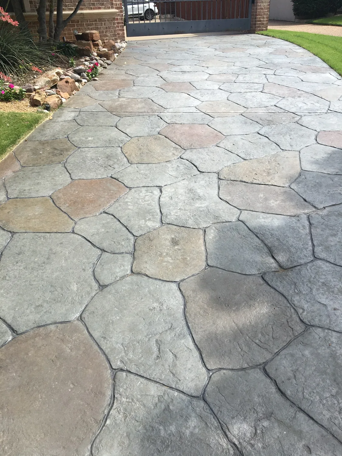 Stamped and hand-colored concrete driveway with a flagstone pattern and sealed finish by Lucky's Concrete